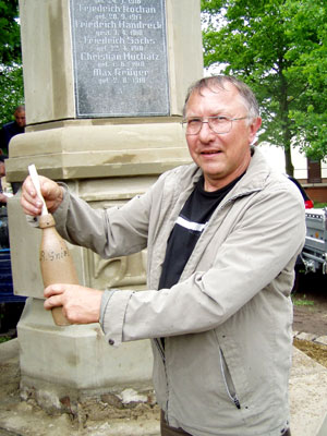 Der Müschener Ortsbürgermeister Heinz Budischin bestückt die historische Flasche mit einem neuen Dokument