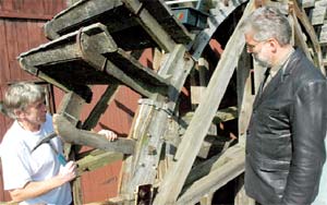 Stadtverordneter Hagen Strese (CDU) fachsimpelt mit Jochen Rädisch (l.) über die Konstruktion des sechs Meter großen Mühlenrades. Etliche defekte Schaufelspieße hat der geschickte Handwerker schon erneuert