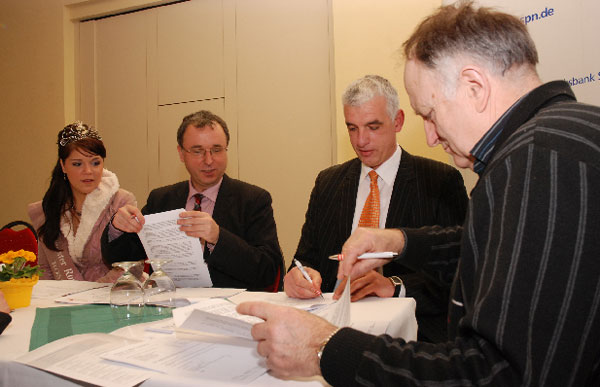 Romy I schaut zu, wie Bürgermeister Dr. Jürgen Goldschmidt, Frank Baer von der Volksbank Spree-Neiße und Hans-Rainer Engwicht vom Förderverein des Rosengartens die Verträge zum Brunnenbau unterzeichnen 		Foto: M.K.