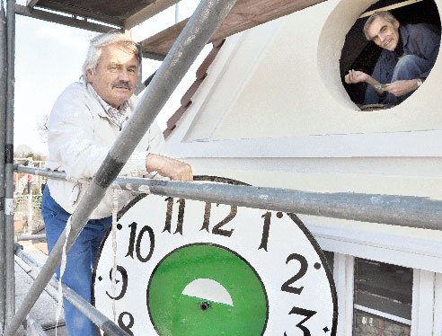 Das Zifferblatt der alten Kolkwitzer Rathausuhr haben Uhrmacher Kalle Schlodder - im Uhrloch - und sein Helfer Karl-Heinz Praß am Donnerstag montiert. Zur Uhrenumstellung in dieser Nacht zum Sonntag, bei der die Uhren um eine Stunde vorgestellt werden (von zwei auf drei Uhr), wird die elektromechanische Uhr noch nicht ticken. Erst wenn die Bauarbeiten beendet sind und der Strom wieder anliegt, zeigt sie wieder die Zeit. Die Verbindung zur Stundenglocke auf dem Dach bleibt aber auf Wunsch von Bürgermeister Fritz Handrow gekappt. Die Uhr ist Baujahr ca. 1920 der Firma Korfhage & Söhne. Nach Kolkwitz kam sie im Juni 1928 vom Bahnhof Bruchmühle (damals Provinz Hannover)