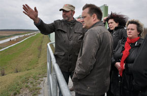 Beißender Wind peitschte Brandenburgs Infrastrukturminister Jörg Vogelsänger ins Gesicht, als er sich am Donnerstag in Grießen die Lebensbedingungen von Ortsvorsteher Hartmut Fort (li.) erklären ließ. Dabei hatte er nach dem Regen noch einen günstigen Zeitpunkt erwischt, am Vormittag trug der kräftige Wind zusätzlich eine dichte Staubwolke in die Tagebau-Randgemeinde. Der Grießener Handwerker hatte den Minister mit Hilfe der Landtagsabgeordneten Monika Schulz-Höpfner (re.) eingeladen. Zur Diskussionsrunde mit Grießener, Kerkwitzer und Groß Gastroser Einwohnern kam auch die Peitzer Amtsdirektorin Elvira Hölzner. Die Schutzwand mit dem Grüngürtel auf der Dorfseite schafft für die Grießener kaum spürbare Entlastung der Lärm- und Staubbelastung, erfuhr der Minister. In einer überwiegend sachlich geführten Runde schilderten Betroffene im Bürgerhaus den zermürbenden Kampf bei Hausschäden, Bodenabsenkungen und den erniedrigenden Betteleien um Unterstützung beim Erhalt der Infrastruktur. 	Foto: Jens Haberland