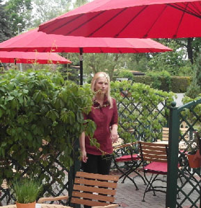 Restaurantfachfrau Susanna Kowalewski ist eine von neun Mitarbeitern des Hotels und deckt die Terrassenstühle mit roten Sitzkissen ein. Rote Sonnenschirme runden das Garten-Ambiente ab 