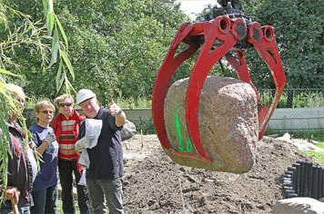 Peter Dreßlers Autokran hebt einen schönen Findling auf seinen neuen Platz. Rainer Wiegank (mit Helm) dirigiert ihn. Zahsower Helfer sind dabei Reinhard Oßmann, Angela Lohs und Teresa Fischer 	Foto: Rudolf Fischer